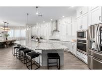 Bright kitchen features white cabinets, granite counters, a large island, and stainless steel appliances at 11818 W Luxton Ln, Avondale, AZ 85323