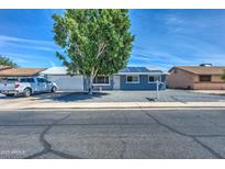 Charming single-story home with desert landscaping, blue exterior, mature shade tree, and solar panels at 1740 W Crescent Ave, Mesa, AZ 85202
