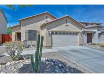 Charming single-story home featuring a two-car garage, desert landscaping, and a cozy front porch seating area at 20338 N 262Nd Ave, Buckeye, AZ 85396