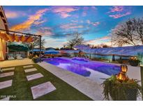 Inviting pool area with desert-themed mural, cozy seating, and vibrant sunset creates a relaxing backyard oasis at 24066 N 167Th Ln, Surprise, AZ 85387