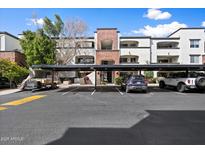 Modern apartment building with covered parking and manicured landscaping under a bright blue sky at 3302 N 7Th St # 211, Phoenix, AZ 85014