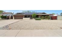 Charming single-story home featuring a gravel front yard, solar panels and a two-car garage at 3830 E Desert Cove Ave, Phoenix, AZ 85028