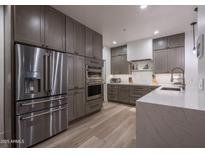 Modern kitchen featuring stainless steel appliances, wood floors, and light countertops at 6703 E Soaring Eagle Way, Scottsdale, AZ 85266