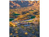Sweeping aerial view of a luxurious home overlooking the golf course and desert mountains at sunset at 9643 E Legacy Ridge Rd, Scottsdale, AZ 85262