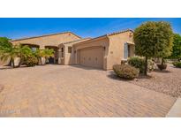 Charming single-story home featuring desert landscaping, a brick driveway, and an attached two-car garage at 14390 W Desert Flower Dr, Goodyear, AZ 85395