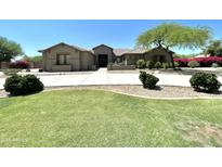 Charming single-story home featuring a lush green lawn, mature landscaping, and a circular driveway at 14539 W Becker Ln, Surprise, AZ 85379
