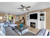 Open-concept living room featuring a fireplace, ceiling fan, and seamless transition to the dining area at 16739 E El Lago Blvd # 103, Fountain Hills, AZ 85268
