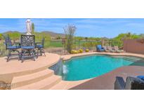 Stunning backyard pool with waterfall feature, seating and beautiful desert golf course views at 2452 W Muirfield Dr, Anthem, AZ 85086