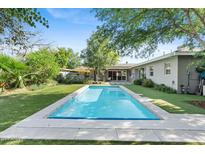 Inviting backyard pool with a modern patio, framed by lush landscaping and a well-maintained lawn at 252 E Orange Dr, Phoenix, AZ 85012