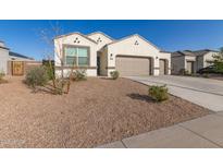 Charming single-story home with a well-maintained yard and a two-car garage, set against a clear blue sky at 3165 N 306Th Ln, Buckeye, AZ 85396