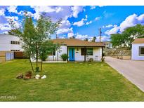 Charming single-story home with a well-manicured lawn, desert landscaping, and a bright blue front door at 4630 N 12Th Pl, Phoenix, AZ 85014
