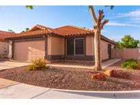Beige home with a 2-car garage, driveway, and desert landscaping at 910 W Redondo Dr, Gilbert, AZ 85233