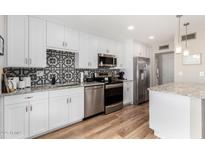Modern kitchen with white cabinets, stainless steel appliances, granite countertops, and decorative backsplash at 17822 N Del Webb Blvd, Sun City, AZ 85373