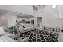Bright living room featuring an open floor plan, modern staircase, and access to the kitchen at 2377 S 245Th Dr, Buckeye, AZ 85326
