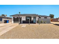 Charming single-story home featuring a black garage door, desert landscaping, and a welcoming covered entry at 3320 E Claire Dr, Phoenix, AZ 85032
