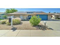 Charming brick home featuring a well-maintained yard, solar panels and a bright blue garage door at 4023 W Joan De Arc Ave, Phoenix, AZ 85029