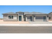 Contemporary home featuring a three-car garage, modern door, and stone accents at 18716 N 269Th Ln, Buckeye, AZ 85396