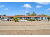 Charming single-story home featuring a beautiful blue exterior, a well-manicured front yard, and a classic front door at 140 W University Dr, Mesa, AZ 85201