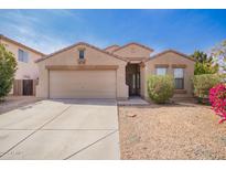Tan single-story home with a two-car garage, desert landscaping and some greenery under a blue sky at 1541 W Lynne Ln, Phoenix, AZ 85041