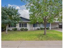 Charming single-story home with lush green lawn, mature trees, and covered carport at 2425 W Shady Glen Ave, Phoenix, AZ 85023