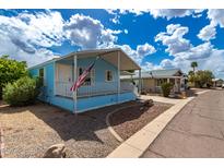 Light blue home featuring a covered porch with white railing and desert-style landscaping in a sunny neighborhood at 201 S Greenfield Rd # 144, Mesa, AZ 85206