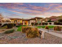 Beautiful single-story home featuring stone accents, a lush lawn, and a charming walkway, all beneath a colorful sunset sky at 911 E Desert Inn Dr, Chandler, AZ 85249