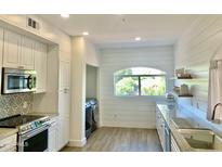 Bright kitchen features white cabinets, light countertops, stainless steel appliances, and an arched window at 8653 E Royal Palm Rd # 2010, Scottsdale, AZ 85258