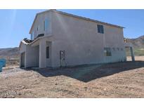 Side view of a two-story stucco home with a garage and a balcony on an unfinished lot at 3835 W Fox Rd, Laveen, AZ 85339