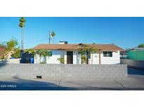 Charming single-story home with a white exterior, brown roof, palm trees, and a block wall in front at 2019 W Wayland Rd, Phoenix, AZ 85041