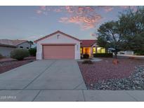Inviting single-story home featuring a two-car garage and well-maintained desert landscaping under a colorful sunset sky at 20301 N Queen Palm Ln, Surprise, AZ 85374