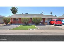 Charming red brick home featuring manicured front yard, tidy landscaping, and a cozy covered porch at 3413 W Ocotillo Rd, Phoenix, AZ 85017