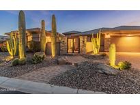 Inviting front entrance featuring desert landscaping, a stone gated entry, and warm exterior lighting at 41424 N Club Pointe Dr, Anthem, AZ 85086