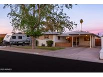 Charming single-story home featuring a covered porch and carport, complemented by mature landscaping and RV parking at 4527 N 12Th Ave, Phoenix, AZ 85013