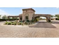 Elegant gated community entrance featuring stone archway, water fountain, and lush landscaping at 18502 N 98Th Way, Scottsdale, AZ 85255