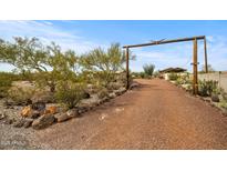 Expansive circular gravel driveway leading to the home with desert landscaping and wood beam entry at 39606 N 3Rd Ave, Phoenix, AZ 85086