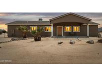 Charming single-story home featuring desert landscaping, a covered porch, and warm exterior lighting at 54463 W Sunburst St, Maricopa, AZ 85139