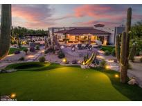 Expansive backyard with putting green, pool, desert landscaping, and cozy outdoor living area at dusk at 7788 E Morning Vista Ln, Scottsdale, AZ 85266