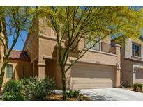 Tan two-story home with a two-car garage and a small balcony, accented by a yellow flowering tree at 1564 W Redwood Ln, Phoenix, AZ 85045