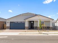 Inviting single-story home with a blue garage door, desert landscaping, and a covered front porch at 4020 S 176Th Dr, Goodyear, AZ 85338
