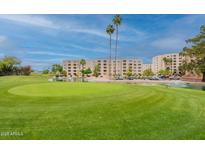 Well-manicured golf course with lush green grass, pond, and residential buildings in the background at 7960 E Camelback Rd # 110, Scottsdale, AZ 85251