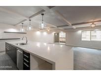 Bright open kitchen featuring modern island, sleek countertops, and contemporary lighting, and gray tile flooring at 7960 E Camelback Rd # 110, Scottsdale, AZ 85251