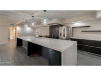Spacious kitchen features a large island, stainless appliances, and modern lighting and gray tile flooring at 7960 E Camelback Rd # 110, Scottsdale, AZ 85251