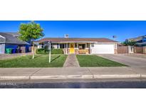Charming single-story home with a well-manicured lawn, brick pathway, and a yellow front door at 1357 S Loma Vis, Mesa, AZ 85204