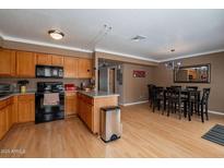 Eat-in kitchen featuring wood cabinets, black appliances and a breakfast bar with pendant lighting at 2875 W Highland St # 1152, Chandler, AZ 85224