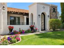 Charming home entrance with a decorative iron gate, well-kept lawn, and vibrant floral accents at 8719 E San Marcos Dr, Scottsdale, AZ 85258