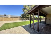 Serene backyard with artificial turf, gravel, and a covered patio for outdoor relaxation and enjoyment at 14017 N 40Th Ave, Phoenix, AZ 85053