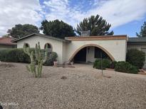 Charming single-story home featuring a desert landscape and unique arched doorway at 4718 W El Caminito Dr, Glendale, AZ 85302