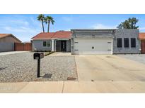 Charming single-story home featuring desert landscaping, a red-tiled roof, and a two-car garage at 10010 N 64Th Ave, Glendale, AZ 85302