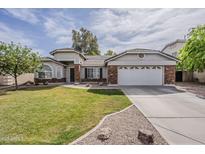 Charming single-story home with lush green lawn, brick accents, and attached two-car garage at 4215 S Marisol Ln, Gilbert, AZ 85297