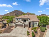 A tan, two story home with a three car garage, desert landscaping, and a mountain in the background at 5042 W Lariat Ln, Phoenix, AZ 85083